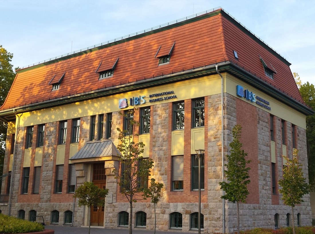 The International Business School building in Budapest, students sitting on the curved bench in the courtyard outside
